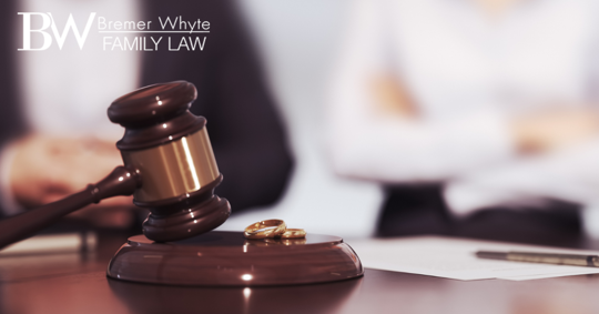 Image of gavel, wedding rings and couple in the background