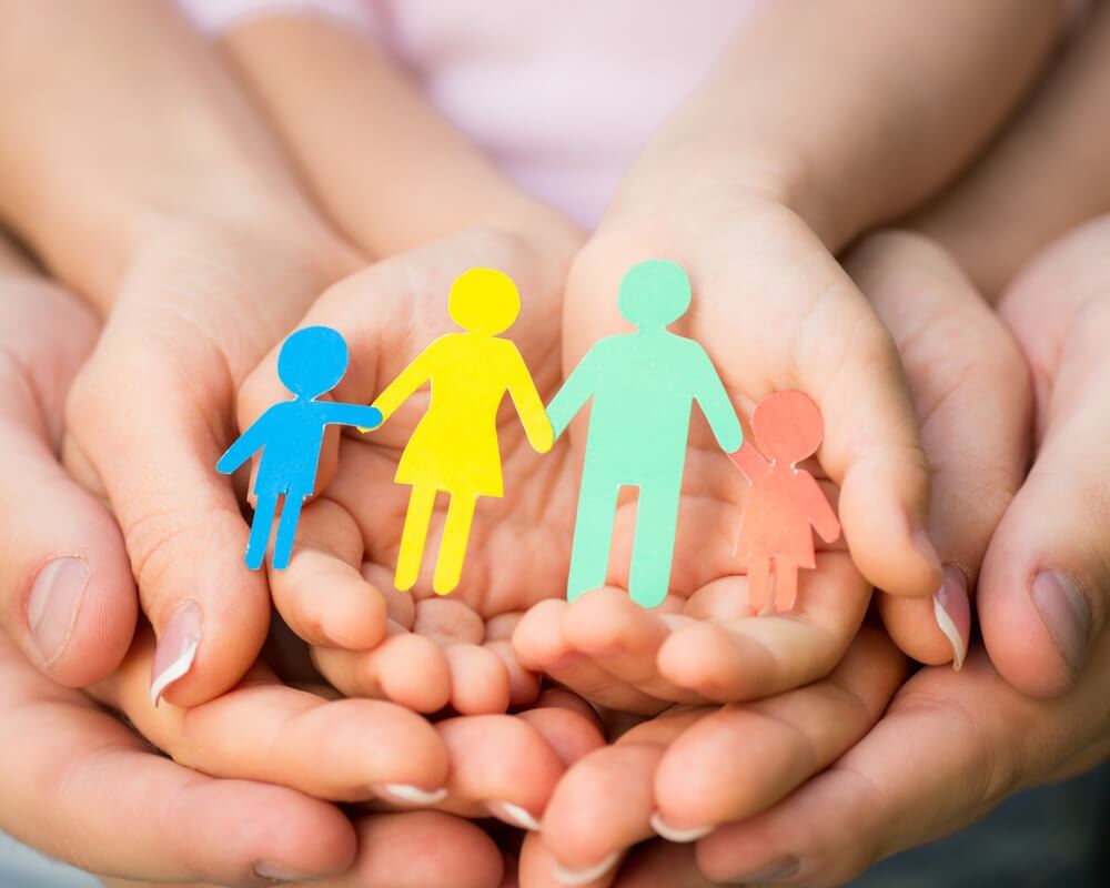 A family holds a family of paper dolls symbolizing adoption